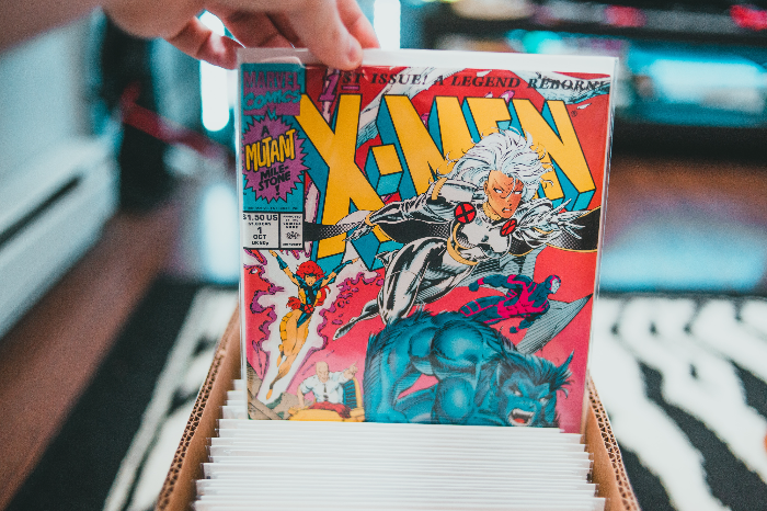 a red comic with the title of Xmen being pulled from a box of comic books